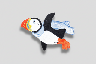 Embroidered patch of a puffin with colorful beak on a white background