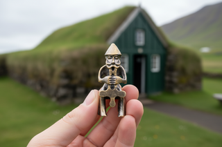 Metallic figurine of a character holding an ankh on a white background