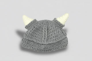 Gray knit baby hat with white horns and a brand tag on a white background