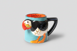 Iceland puffin mug with colorful 3D puffin design, black handle, and orange interior, fun Iceland souvenir coffee cup.

