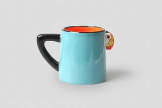 Iceland puffin mug with colorful 3D puffin design, black handle, and orange interior, fun Iceland souvenir coffee cup.