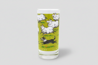 Iceland sheep glass milk cup with playful cartoon sheep design on green background, Iceland souvenir drinking glass.