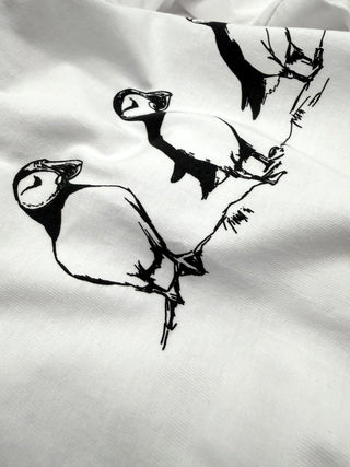 Black ink drawings of birds on a white fabric background