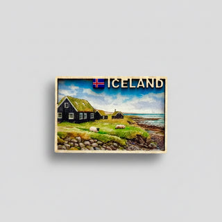 Fridge magnet with a scenic view of Iceland featuring a house and sheep, on a white background.