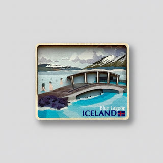Fridge magnet with illustration of a wooden bridge over water and mountains, featuring 'Blue Lagoon Iceland' text.