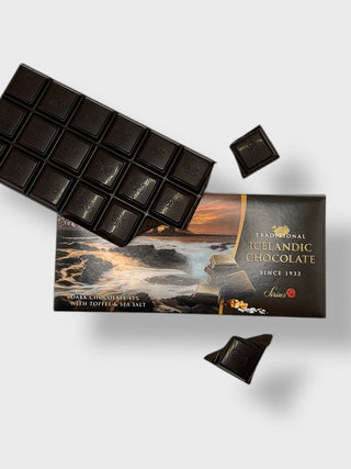 Traditional Icelandic dark chocolate 45 percent with toffee and sea salt, partially unwrapped, showing dark chocolate squares and coastal landscape packaging