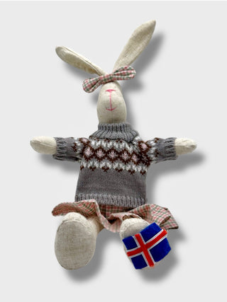 Toy rabbit wearing a sweater with an Icelandic flag on a light gray background