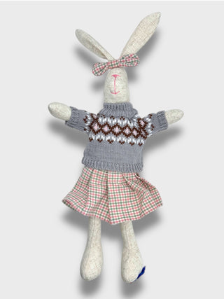 Stuffed bunny toy wearing a sweater and skirt on a light gray background