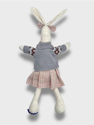 Toy rabbit with a knitted sweater and plaid skirt on a light gray background
