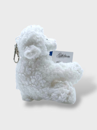 White fluffy keychain with a tag on a light gray background