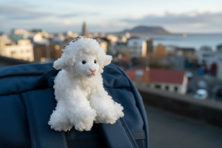 White plush lamb keychain with a tag on a light gray background