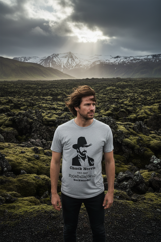 Man wearing a t-shirt with a graphic design in a landscape with mountains and moss-covered ground.