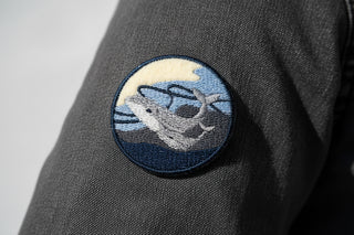 Embroidered patch of a shark in the moonlit ocean on a light gray background