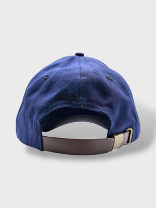 Blue baseball cap with a brown strap on a light gray background