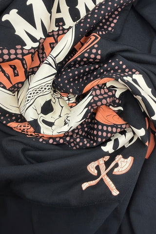 Close-up of a black fabric with white and orange designs, including skulls and crossbones.