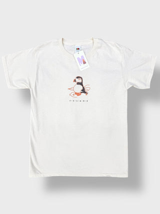 An off-white short-sleeve crewneck t-shirt featuring a central graphic of a puffin with orange and black details, and the word 'EISLAKNA' printed below. The shirt is displayed flat against a light gray background with a soft drop shadow.