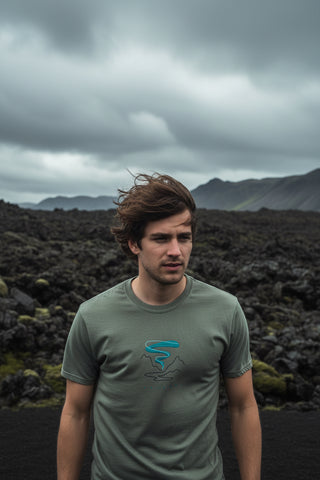 An olive green short-sleeve t-shirt with a small graphic on the center chest depicting a turquoise river winding through gray mountains, with 'THE RIVER' printed below. The shirt is shown flat against a white background with a soft drop shadow.