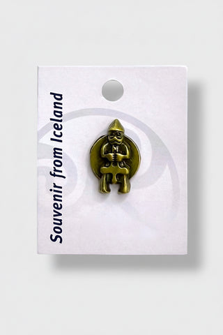 A small gold-colored souvenir pin shaped like a seated figure of Thor, mounted on a white backing card printed with 'Souvenir from Iceland' 