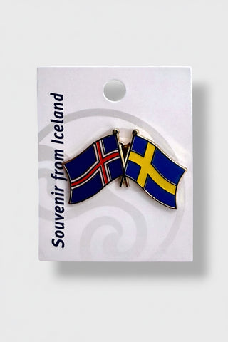 A souvenir enamel pin depicting the flags of Iceland and Sweden, mounted on a white display card. The card features the text 'Souvenir from Iceland' 