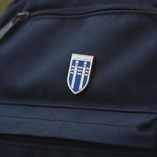 An enamel pin shaped like a shield, featuring the Reykjavík city emblem in blue, white, and silver, mounted 