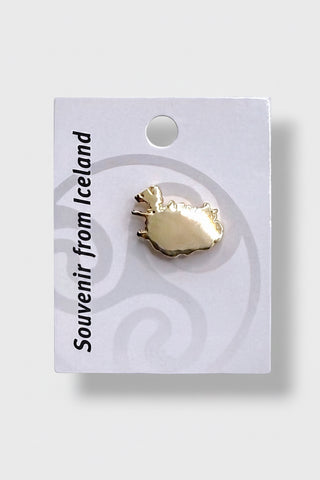 A small gold-toned souvenir pin shaped like the map of Iceland, mounted on a white display card with the text 'Souvenir from Iceland' 