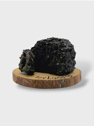 Black volcanic rock on a wooden stand with 'Iceland' engraved, on a white background