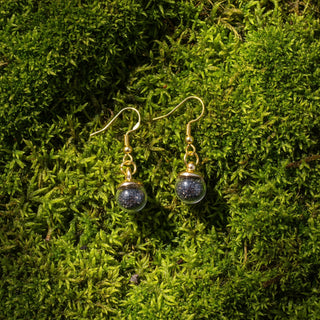 Pair of earrings on a black card with 'Icelandic Sand' branding on a light gray background
