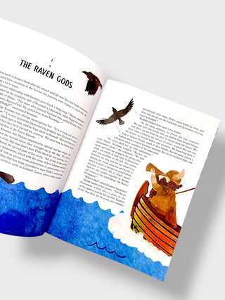 An open children's book spread showing the chapter 'The Raven Gods' with text and watercolor illustrations of ravens and a figure in a boat on blue water.