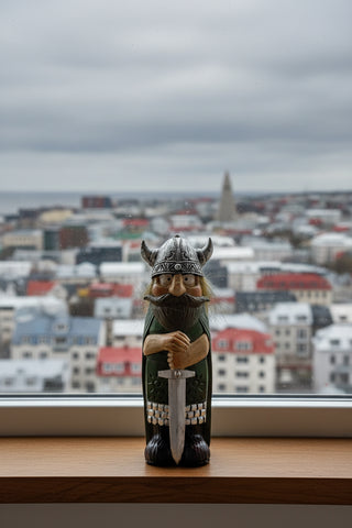 Hand-painted polyresin Icelandic Viking figurine with silver helmet, green cloak, long beard, and both hands resting on a large sword, 18 cm (7.09 in) tall.