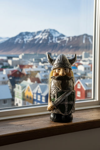 A small Viking figurine with a silver horned helmet, long blonde hair, brown beard, and armor with a green shield