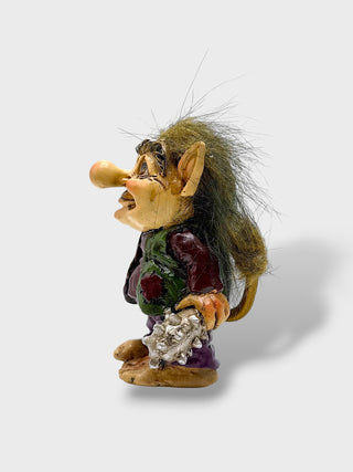 Hand-painted polyresin Icelandic troll figurine holding a sea shell, wearing a purple outfit with a green vest, fluffy hair, and a smiling face, 9 cm (3.54 in) tall.
