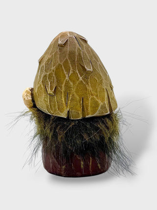 A small decorative gnome figurine with a textured olive-green conical hat, a dark brown and black faux-fur beard, and a reddish-brown base, shown against a light gray background.