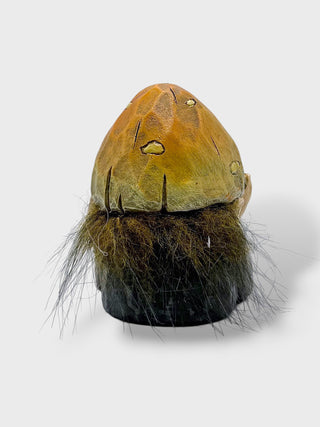 A small decorative object featuring a rounded tan top with stitched details and a dense black bristle or faux-fur base, photographed against a plain light gray background.