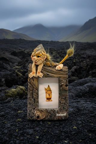 Elf figurine with a broom inside a wooden frame labeled 'Iceland'.