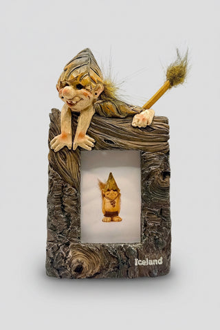 Elf figurine with a broom inside a wooden frame labeled 'Iceland'.