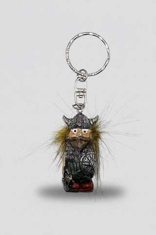 A small decorative keychain featuring a Viking figurine with a silver-toned metal ring and clasp, brown faux fur trim, and a patterned green and red outfit, shown on a white background.
