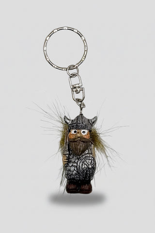 A small viking keychain charm with a carved wooden face, horned helmet, chain, and attached brown and beige fur, shown on a plain white background.