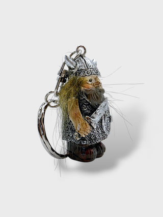 A small fantasy keychain charm shaped like a bearded dwarf or gnome in silver-toned armor, with tan fur and long white whiskers, attached to a silver split ring on a light gray background.