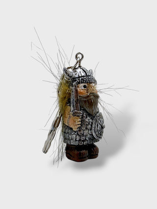 A small Viking warrior charm or pendant with a silver-toned helmet and armor, brown beard and boots, and a yellow-brown fur detail, shown on a light gray background.