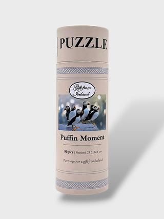 A cylindrical puzzle box for 'Puffin Moment' 90-piece puzzle, featuring a cream-colored label with blue patterns and an image of puffins, set against a light gray background.