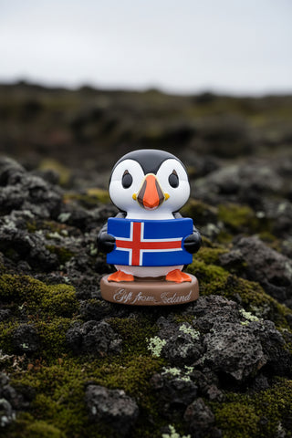 Cute Iceland puffin figurine holding the Icelandic flag on a Gift from Iceland base