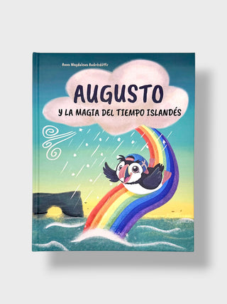 A children's book cover titled "AUGUSTO Y LA MAGIA DEL TIEMPO ISLANDÉS" by Ann-Margareta Jöbéléité, featuring a colorful illustration of a puffin sliding down a rainbow in the ocean with a pink cloud above.