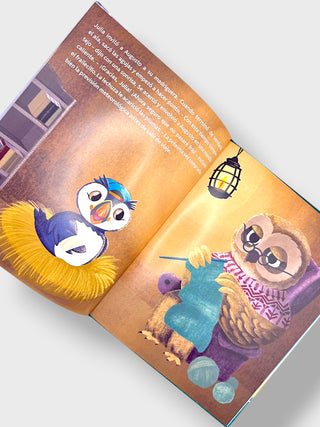 An open children's book with colorful illustrated pages, photographed at an angle on a light gray background. The left page shows a penguin in a yellow nest, and the right page shows a sloth knitting with yarn balls under a lantern.